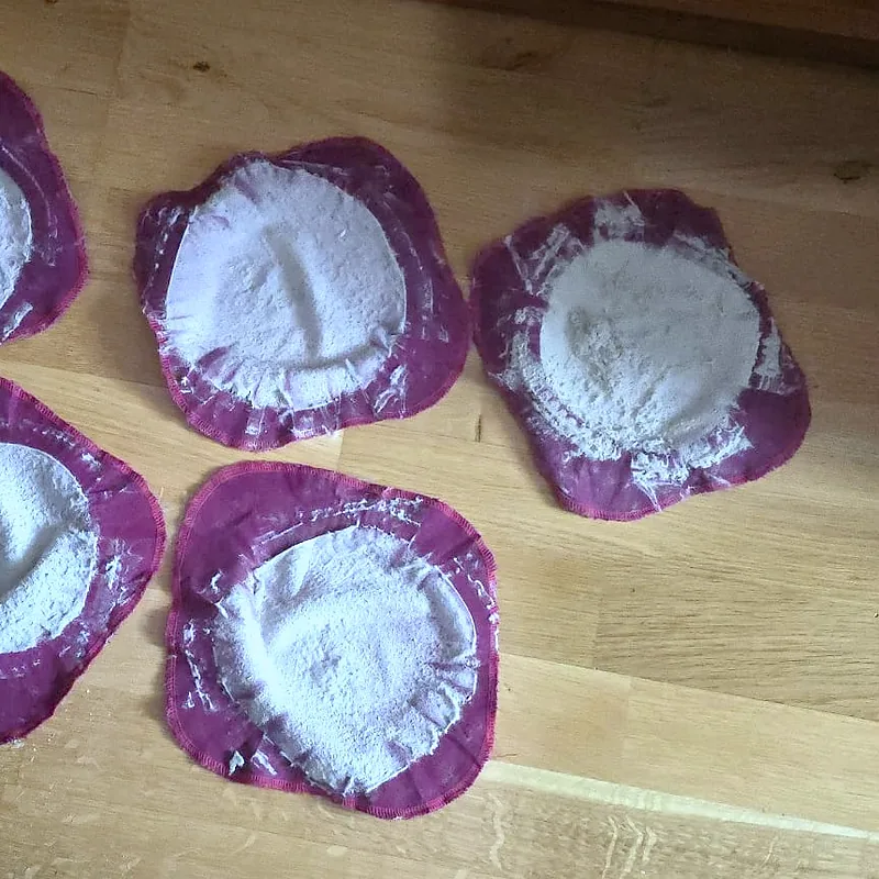 Fünf Staubfilter nach Matratzenreinigungen auf einem Holzboden, zwei davon am linken Bildrand angeschnitten