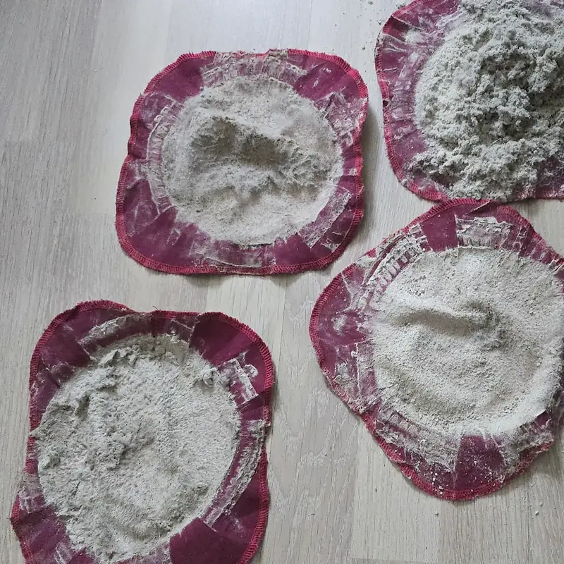 Vier Staubfilter nach Matratzenreinigungen auf einem hellen Fußboden, drei davon am Bildrand angeschnitten